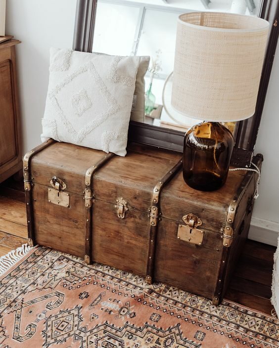 Malle posée sur un tapis avec miroir et coussin dessus